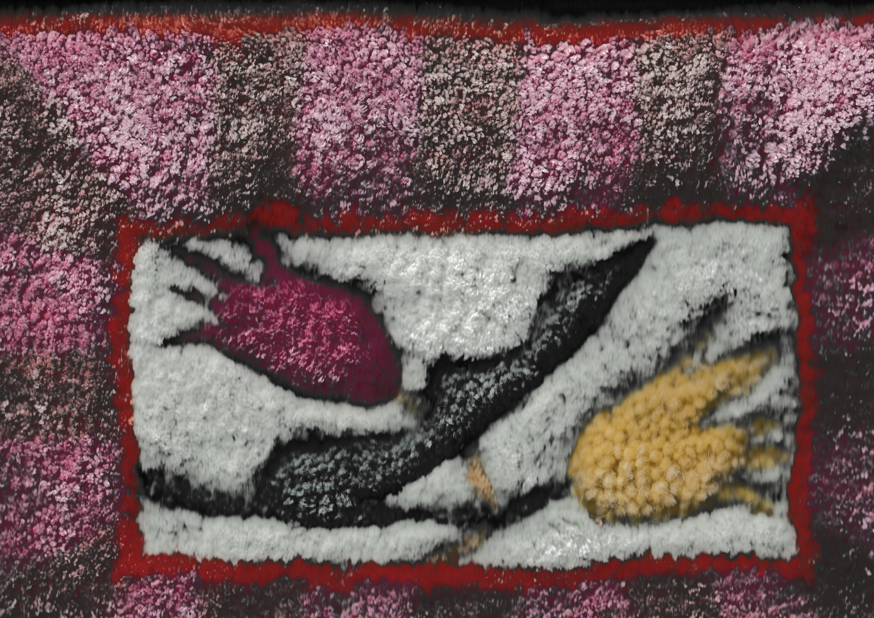 Close-up detail of a hand-tufted rug: abstract pink, white, black and yellow organic forms within a red border, on a pink-and-black ground.